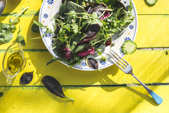 Spring salad of baby spinach, herbs, arugula and lettuce on plate, olive oil