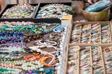 Shot of expensive gemstone jewelry. Rings, necklaces and bracelets made of peridot and azurite stones, red coral, sapphire, rose quartz and moonstone. Powerful, healing crystals, luxury background