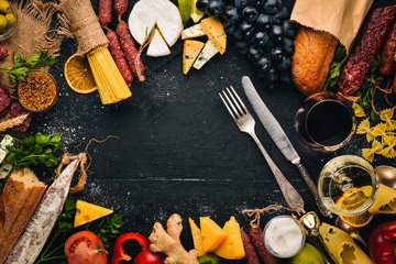Assorted cheeses, sausages, wines, traditional spices and fresh vegetables on a wooden background. Cheese brie, blue cheese, gorgonzola, fuete, salami. Italian and Spanish Cuisine. Free space.