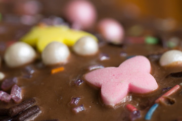 Closeup of sugar butterfly and birthday cake icing with colourful decoration – side view
