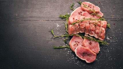 Raw meat Beef fillet with rosemary and spices on a black wooden background. Top view. Free space...