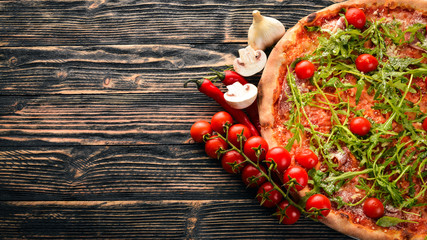 Pizza Primavera. Cherry tomatoes, arugula, cheese. On a wooden background. Top view.