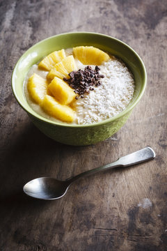 Bowl of fruit smoothie garnished with pineapple slices, coconut flakes and chocolate shaving