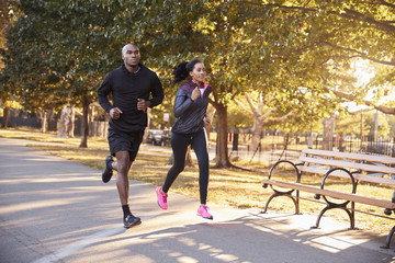 Young black couple jogging in a Brooklyn park - obrazy, fototapety, plakaty