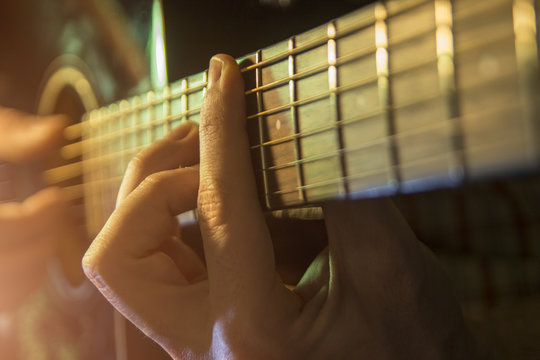 Male hand playing on acoustic guitar. Close-up.