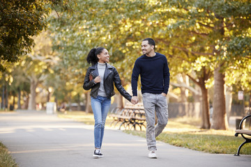 Fototapeta premium Young Hispanic couple walking hand in hand in Brooklyn park