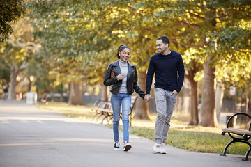 Young Hispanic couple walking hand in hand in Brooklyn park