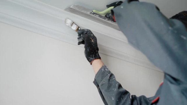 Hired builder is painting celling plinth.