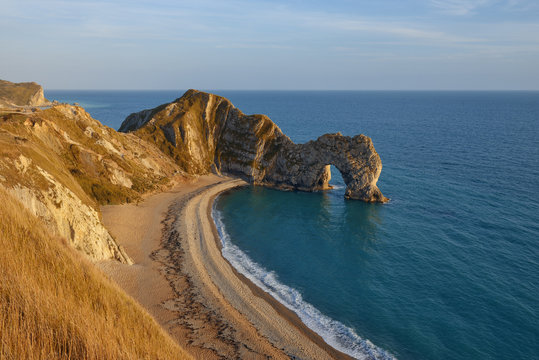 England, Jurassic Coast, Durdle Door, rock arch, beach at warm evening light