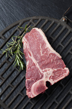 Raw porterhouse steak with rosemary on grill