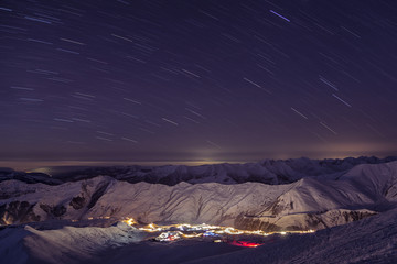 Star trails over the city lights at night in the mountains. Georgia. Gudauri.
