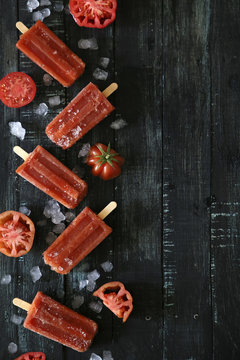 Tomato ice lollies on black wood