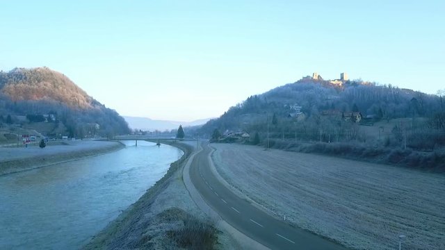 Aerial: Drone taking of parking place near river looking at city caste. Shot in Slovenia near city Celje showing river Savinja and city castle in background.