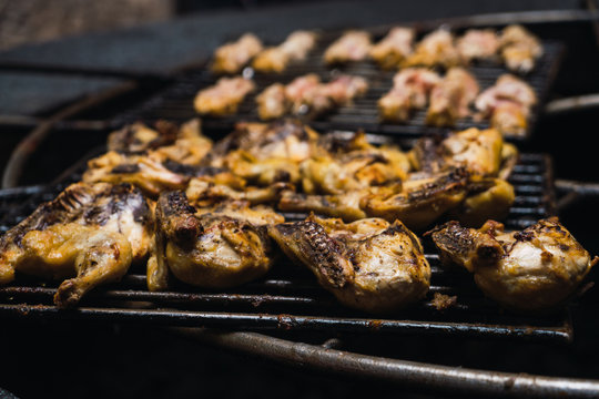 Half-sliced chickens grilling