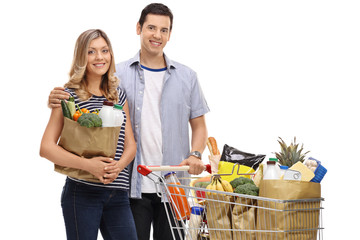 Young couple with shopping bags and a shopping cart filled with groceries