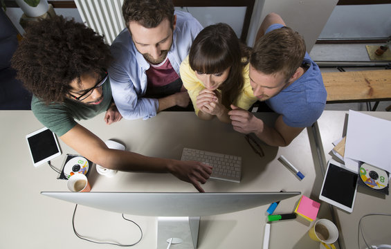Team of creative professionals sitting around computer screen