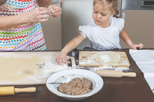 Little girl helps mom make dumplings