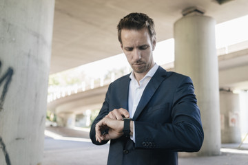 Fototapeta na wymiar Businessman standing at underpass using smartwatch