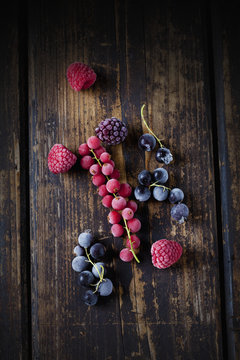 Deep frozen red and black currents, raspberries and blackberries on wood