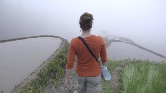 Female tourist walking down a dramatic foggy mountain