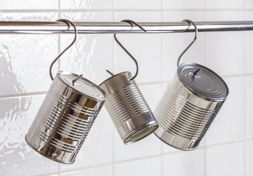 Three preserve cans hanging on meat hooks