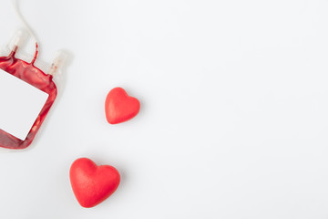 two red hearts near plastic package with blood for transfusion isolated on white background