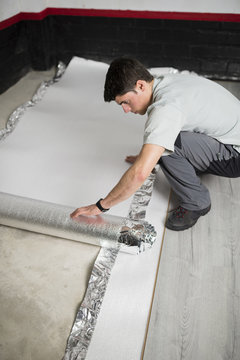 Young man placing a insulating material for a laminate flooring