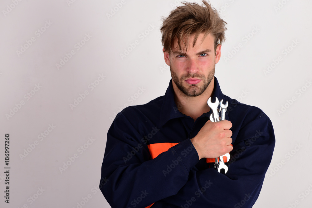 Wall mural Man with serious face in uniform holds wrench tools