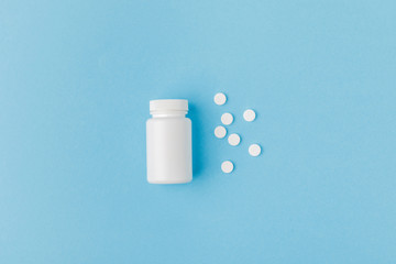 container and scattered pills isolated on blue background