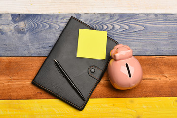 Piggy bank in pink color on colorful wooden background.