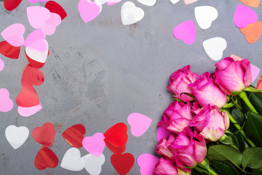 Decorative hearts and pink roses on grey stone background