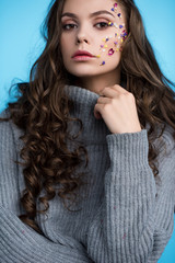 stylish long haired young woman with flowers on face in sweater