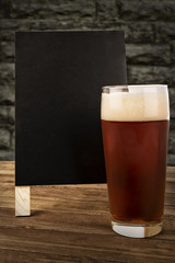 Glass of beer and blackboard disposed on a bar of a restaurant.