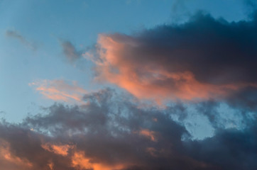 Fototapeta na wymiar Dramatic cloudscape scene at orange sunset, colored sun lights on the blue sky, fluffy clouds