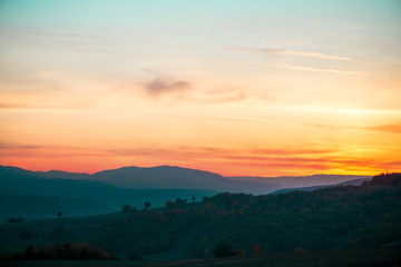 Romantic, bright and colorful sunset over a mountain range in Transilvania. Beautiful, colorful autumn background.