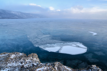 Ice floes floating on the fog water in the lake Baikal. Sunset
