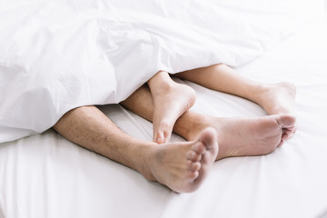 Obraz na płótnie Canvas Close up of couple feet sleeping together on bedroom at early morning. Couple relaxing concept.