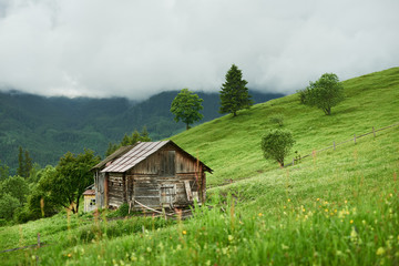 Summer landscape with village house at mountains in cloudy weather.