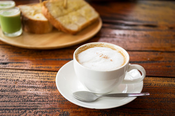 Fototapeta premium Cup of coffee with bread on wooden table