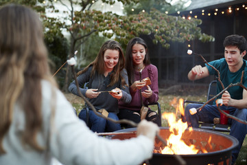 Teenage friends making sÕmores with toasted marshmallows