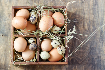 Chicken and quail eggs in a wooden box. Rustic style.