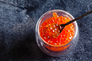 Black and red caviar in glass bowls on ice on the black background