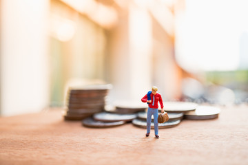 Miniature people, businessman standing on stack coins using as business concept