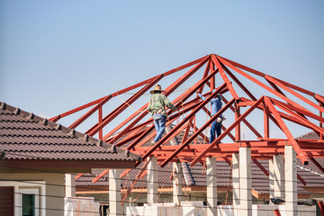 Fototapeta na wymiar welder workers installing steel frame structure of the house roof at building construction site