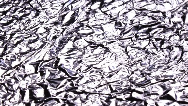 Amazing side view of white metal ripple surface, rotating clockwise with side center. Excellent abstract monochrome background in UHD 4k, 3840x2160. Vibrant meditative image. Crumpled aluminum foil.