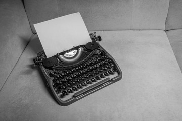 Typewriter ready for use with blank paper installed macro black and white background. Top view