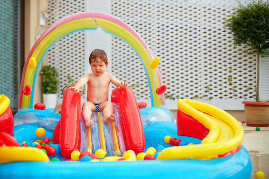 infant baby boy are going to slide in inflatable pool at the patio zone