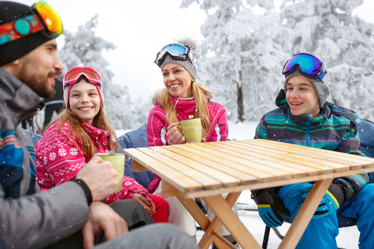 Family on ski terrain drinking tea