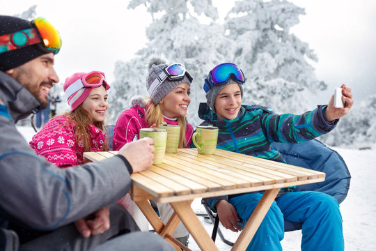 Boy making selfie with family in cafe on ski terrain