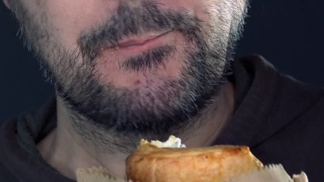 Gluttony concept, hungry adult man eating croissant very fast, habitual excess in eating, close up of mouth